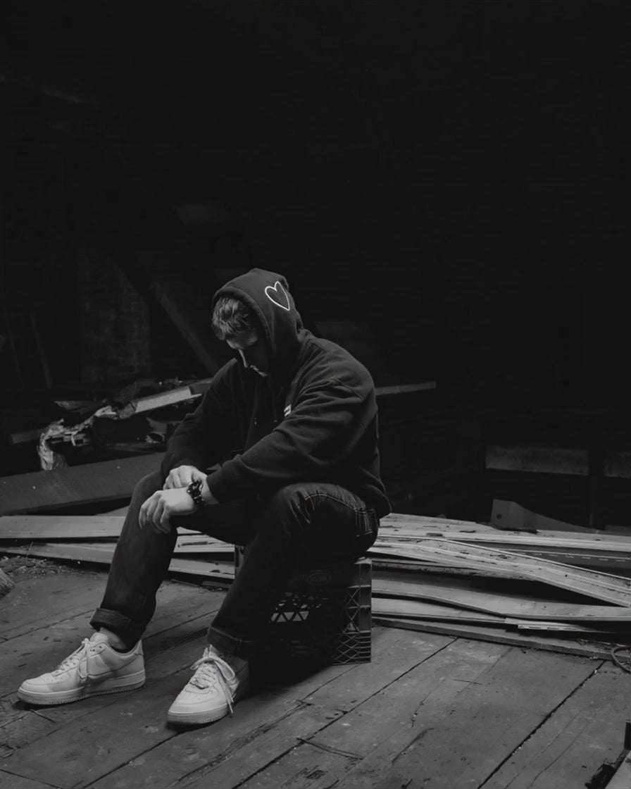 Ryan Zakrzewski seated with his head lowered and hands resting, watch visible on his wrist